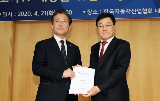 정만기 한국자동차산업협회장(오른쪽)은 21일 서울 서초구 협회에서 성윤모 산업통상자원부 장관에게 코로나19 여파로 인한 자동차 업계 긴급 건의서를 전달했다. <산업통상자원부 제공>